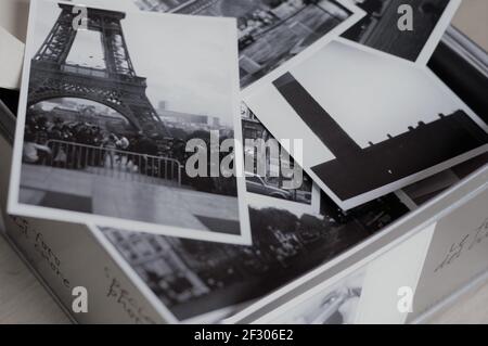 Scatola in metallo piena di foto scattate a Parigi con Tour Eiffel in primo piano in una foto in bianco e nero Foto Stock