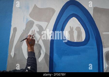 Città di Idlib, Siria. 14 Marzo 2021. L'artista Aziz al-Asmar e i suoi colleghi dipingono un murale che comprende la bandiera dell'opposizione siriana e la parola "Rivoluzione" in arabo, per commemorare 10 anni dall'inizio della guerra civile siriana, durante la quale sono state uccise almeno mezzo milione di persone, oltre un milione di feriti, mentre metà della popolazione del paese è andato in sfollamento. Credit: ANAS Alkharboutli/dpa/Alamy Live News Foto Stock