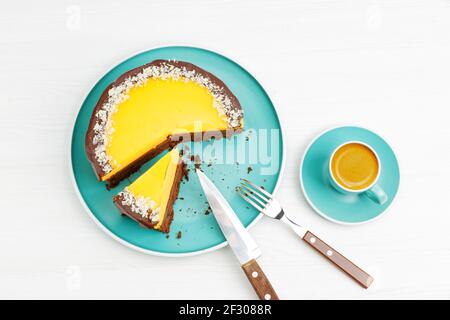 Cioccolato fatto in casa e cheesecake all'arancia cosparsa di fette di mandorle e tazza di caffè espresso su un tavolo di legno bianco. Vista dall'alto. Foto Stock
