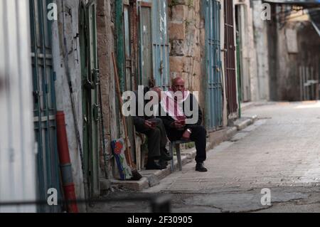 Nablus. 14 Marzo 2021. Uomini palestinesi siedono su una strada vuota nella città di Nablus, in Cisgiordania, il 14 marzo 2021. La Palestina di sabato ha annunciato la decisione di estendere il blocco completo della Cisgiordania per altri cinque giorni, a partire dal 15 marzo, tra i crescenti casi e decessi giornalieri COVID-19. Credit: Nidal Eshtayeh/Xinhua/Alamy Live News Foto Stock