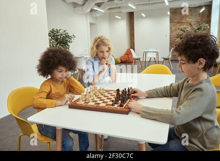Giocatori. Bambini che giocano a scacchi. Piccoli ragazzi seduti al tavolo e giocando a scuola di scacchi Foto Stock