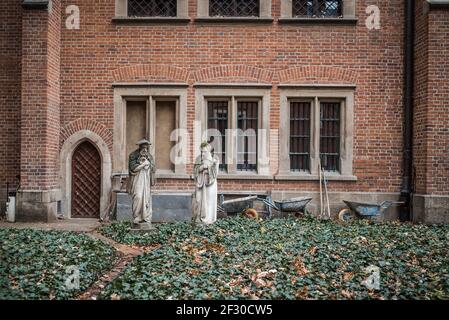 Abbandonate vecchie statue religiose in pietra all'esterno di un edificio vuoto in fase di ristrutturazione ruote e sopra giardino cresciuto guardando triste perso all'aperto sinistra dietro Foto Stock