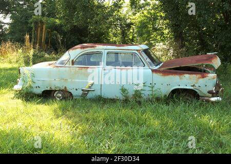 Vecchio modello di un veicolo Ford, corroso, abbandonato su un campo Foto Stock