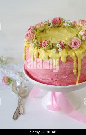 Torta di gelato alla fragola rosa festosa con glassatura al cioccolato giallo e. rose Foto Stock