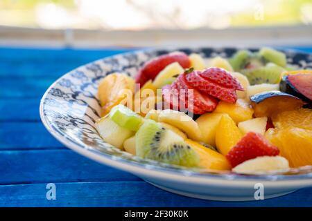 Insalata di frutta naturale e sana con arancia in un piatto vintage su una superficie rustica blu. Concetto di cibo sano, vita sana. vista a 45 gradi, Foto Stock