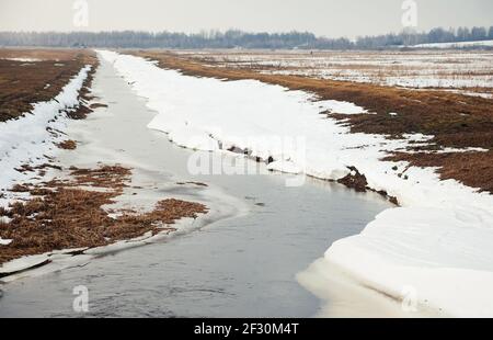 Fiume in primavera, sulla riva della neve. La neve si scioglie con l'arrivo del calore vicino alle rive del fiume. In primavera, il ghiaccio scende il Foto Stock