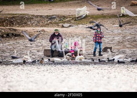 Praga, repubblica Ceca - Marzo 12. Bambini con genitori che giocano con la maschera di protezione del viso nei luoghi pubblici in riva al fiume da Moldau e nutrendo uccelli w Foto Stock