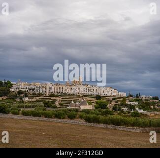 Vista dello skyline di Locortondo in Puglia da un campo di ulivo Foto Stock