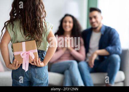 Sorpresa per Mummy. La piccola ragazza che tiene la scatola del regalo dietro la parte posteriore Foto Stock