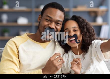 Il padre afroamericano e la sua piccola figlia che prendono selfie divertente Foto Stock