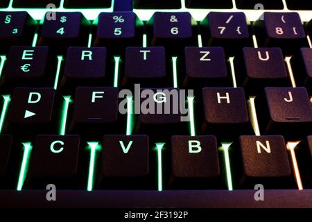 Makro primo piano di tasti illuminati verdi della tastiera del computer (Mettere a fuoco la lettera G del tasto della lettera) Foto Stock