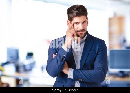 Primo piano di studio di un uomo pensante in piedi in ufficio. Spazio di copia. Foto Stock