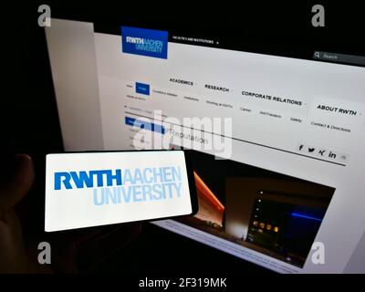 Persona che detiene smartphone con logo di Rheinisch-Westfälische Technische Hochschule Aachen sullo schermo davanti al sito web. Mettere a fuoco il display del telefono. Foto Stock
