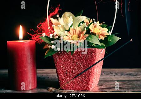 Candela rossa, fiori e bastone profumato Foto Stock