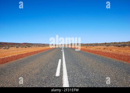 Lunga strada dritta attraverso la desolata Outback, Northern Territory, Australia Foto Stock