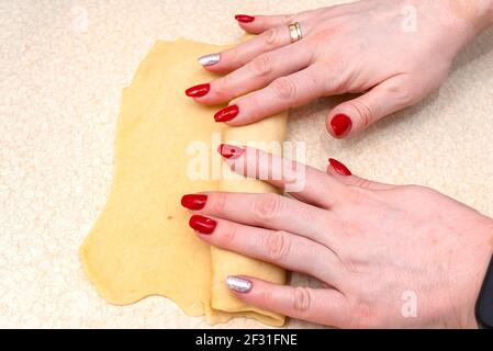 La donna arrotola l'impasto di lievito arrotolato in polpettine con funghi ripieni all'interno. Foto Stock