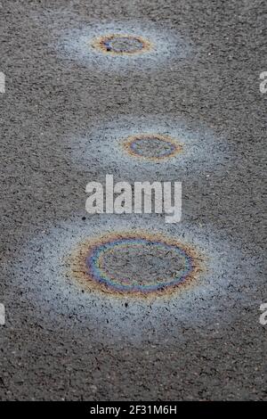 perdite di olio arcobaleno arcobaleno su strada asfaltata bagnata Foto Stock