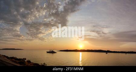 Tramonto arancione sole che splende sopra le isole greche nel Mar Egeo. Panorama vicino Atene in Grecia. Viaggio turistico estivo. Nuvole panoramiche e yacht in calma Foto Stock