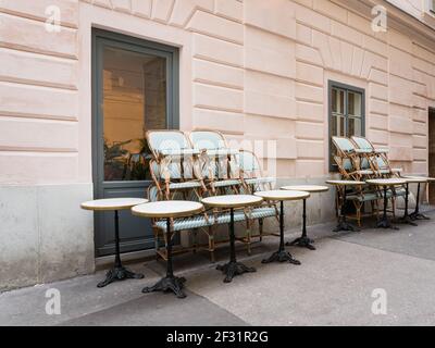 Sedie e sgabelli accatastati sui tavoli di fronte ad un vuoto chiuso ristorante cafè durante Covid-19 Corona pandemic. Foto Stock