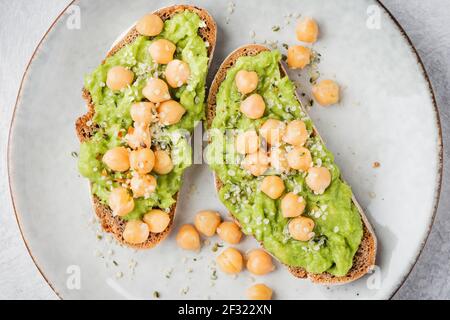 Toast con avocado, semi di canapa e ceci su un piatto Foto Stock