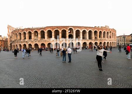 Italia, Verona, turisti che si posano in Piazza Bra con l'Arena o l'Anfiteatro di Verona nel retrocoperto. Foto Stock