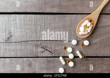 Piatto con omega 3 e integratori vitaminici su cucchiaio di legno sullo sfondo. Concetto di salute. Pillole di vitamina. Foto di alta qualità Foto Stock