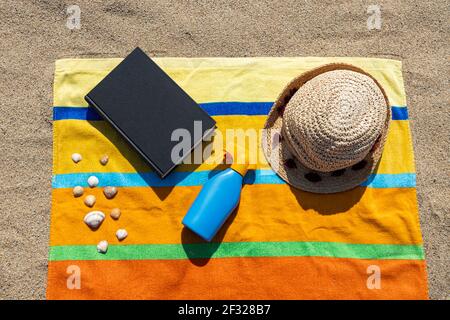 Asciugamano, cappello, crema solare sulla spiaggia. Concetto estivo. Foto Stock