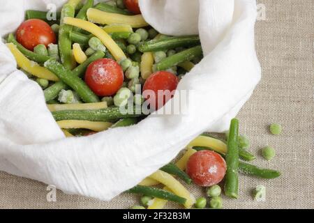 Verdure surgelate in sacchetto di stoffa senza rifiuti di plastica su fondo di tessuto di lino, closeup, conservando avanzi, deposito di cibo ed eco-friendly, riutilizzabile, Foto Stock