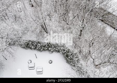 Vista aerea degli alberi ricoperti di neve e patio coperto di neve con tavoli da picnic, inverno a NDG, Montreal, QC Foto Stock