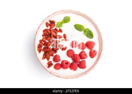 Yogurt con lampone e bacche goji in recipiente in ceramica isolato su sfondo bianco. Vista dall'alto, piatto, primo piano. Foto Stock