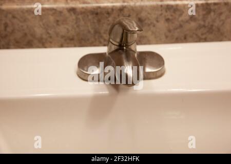 una maniglia argentata per accendere il rubinetto dell'acqua in una casa con un countertop di granito Foto Stock