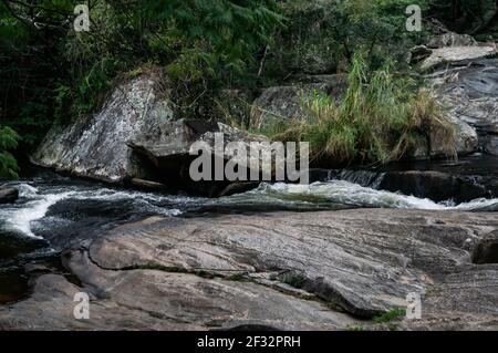 Il flusso d'acqua limpido della cascata di Pimenta che scorre intorno alle formazioni rocciose nella foresta di media Sea Ridge (Serra do Mar). Foto Stock