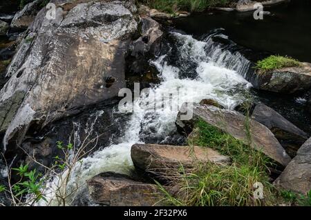 Il flusso d'acqua della cascata di Pimenta che scorre intorno alle formazioni rocciose nella foresta di Serra do Mar nella campagna di Cunha. Foto Stock