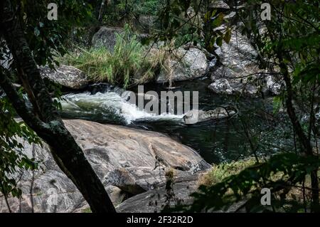 Il flusso d'acqua della cascata di Pimenta che scende tra formazioni rocciose nella foresta di Serra do Mar nella campagna di Cunha. Foto Stock