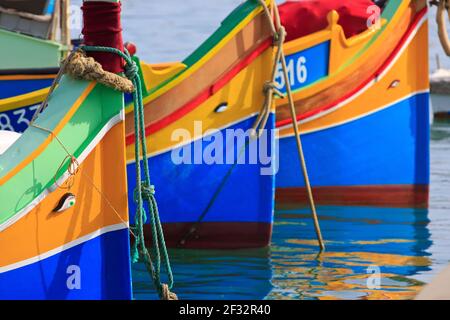 Primo piano della prow di tre luzzijiet (imbarcazioni da pesca tradizionali maltesi) nel porto turistico di Marsaxlokk, Malta Foto Stock