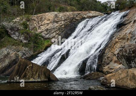 Il flusso d'acqua della cascata di Pimenta che scende sopra le principali formazioni rocciose a goccia nella foresta di Serra do Mar, nella campagna di Cunha Foto Stock