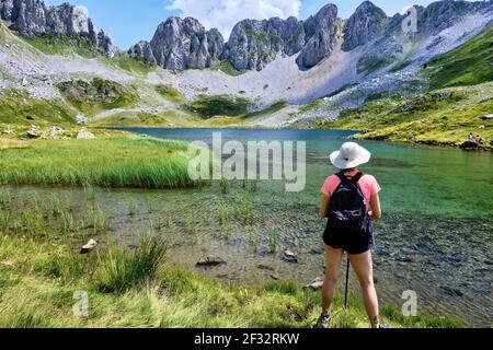 Donna escursionista e montagna lago glaciar. Via IBON de Acherito. Parco Naturale Valles Occidentales. Catena montuosa dei Pirenei. Huesca, Aragona, Spagna, Europa Foto Stock