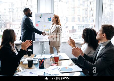 I partner commerciali multirazziali firmano finalmente un importante contratto, giungono ad un accordo dopo i negoziati. Uomini e donne di successo stanno scuotendo le mani, il lavoro di squadra e il concetto di collaborazione Foto Stock