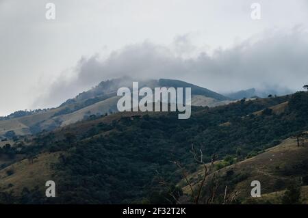 Le fredde nuvole di fronte sulla cima della montagna della regione di Sea Ridge (Serra do Mar) come visto sulla strada per la cascata di Destero. Foto Stock