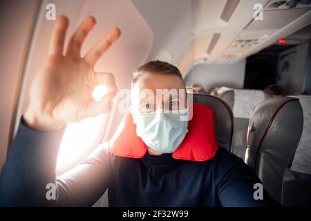 Il passeggero maschile dell'aereo ascolta la musica e gode di un cuscino  per dormire in sedia. Concetto di viaggio con maschera di sicurezza Foto  stock - Alamy