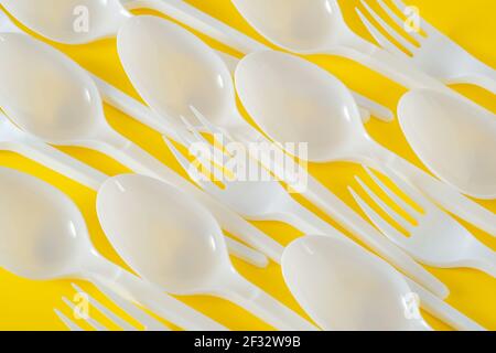 Cucchiai e forcelle in plastica su sfondo giallo Foto Stock