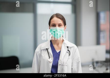 Ritratto di una dottoressa in una clinica che indossa un maschera e abito medico con stetoscopio Foto Stock