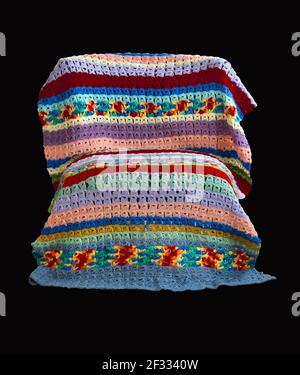 Una coperta a crochet vintage colorata in pizzo con punto a scopino drappeggiato su una sedia creata dall'artista tessile americano Margaret Braaten (1914-2004). Foto Stock