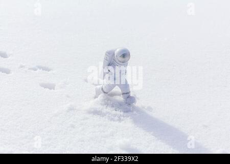 La statuetta di un astronauta esplora con sicurezza la superficie del pianeta alieno. Pianeta freddo coperto di neve. Spazio di copia. Foto Stock