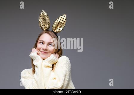 Ritratto femminile di una ragazza carina in orecchie di coniglio sopra uno sfondo grigio Foto Stock