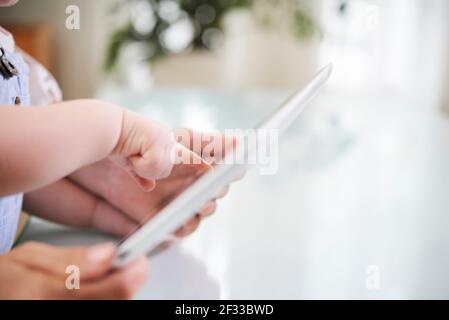 Immagine ravvicinata di madre e bambino che puntano al tablet computer con applicazione sullo schermo Foto Stock