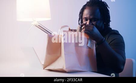 Uomo nero afroamericano che ottiene la consegna del cibo in ufficio. Fast food e pausa pranzo. Foto di alta qualità Foto Stock