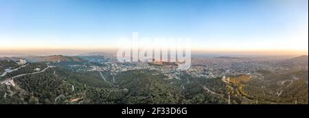 Panorama Aerial drone shot del Monte Tibidabo con vista sulla città Di Barcellona durante il tramonto Foto Stock