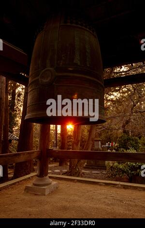 Grande campana di ottone in un tempio giapponese Shinto a Sendai, in Giappone chiamato Rinno-ji Tempio con alberi di pino e il tramonto sullo sfondo Foto Stock