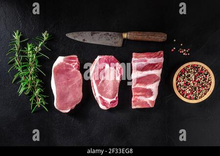 Carne di maiale, tagli diversi con rosmarino e pepe, sparato dall'alto Foto Stock